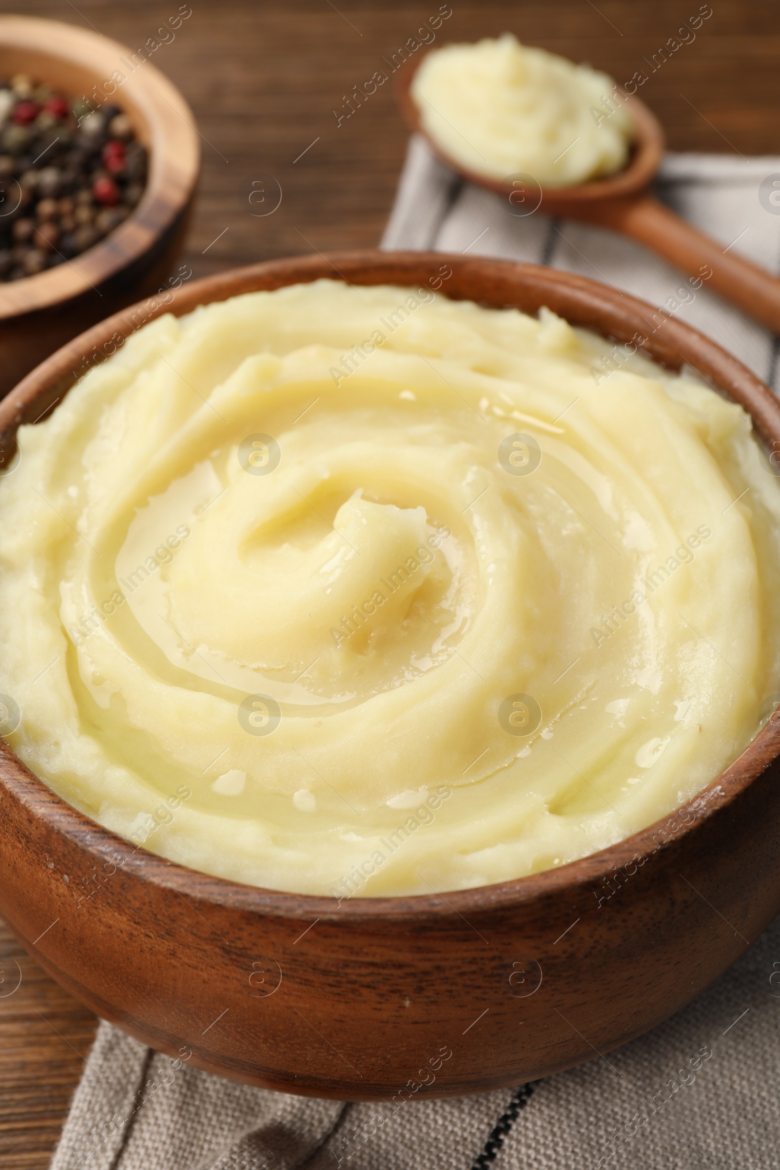 Photo of Bowl of tasty mashed potato and pepper on wooden table, closeup