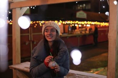 Woman with cup of mulled wine at winter fair. Space for text