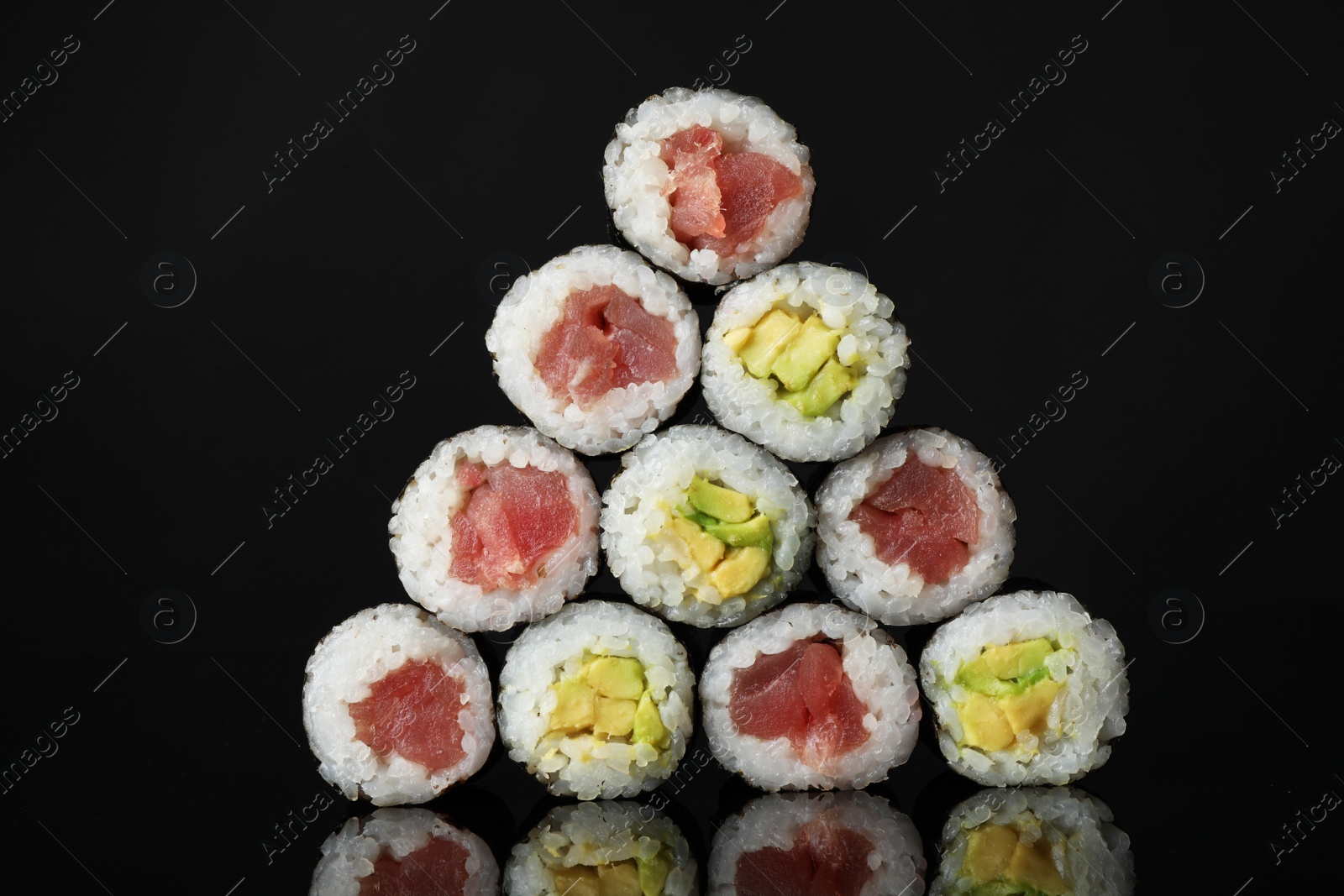 Photo of Delicious sushi rolls on black mirror surface