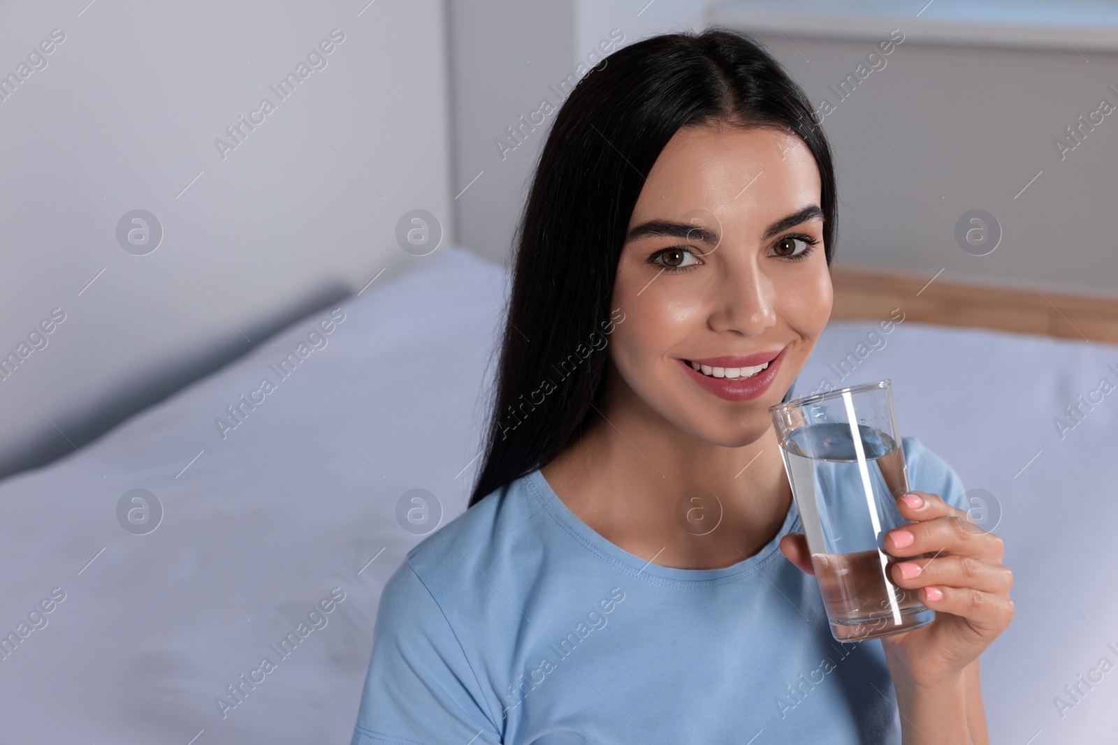 Photo of Young woman with glass of water indoors, space for text. Refreshing drink