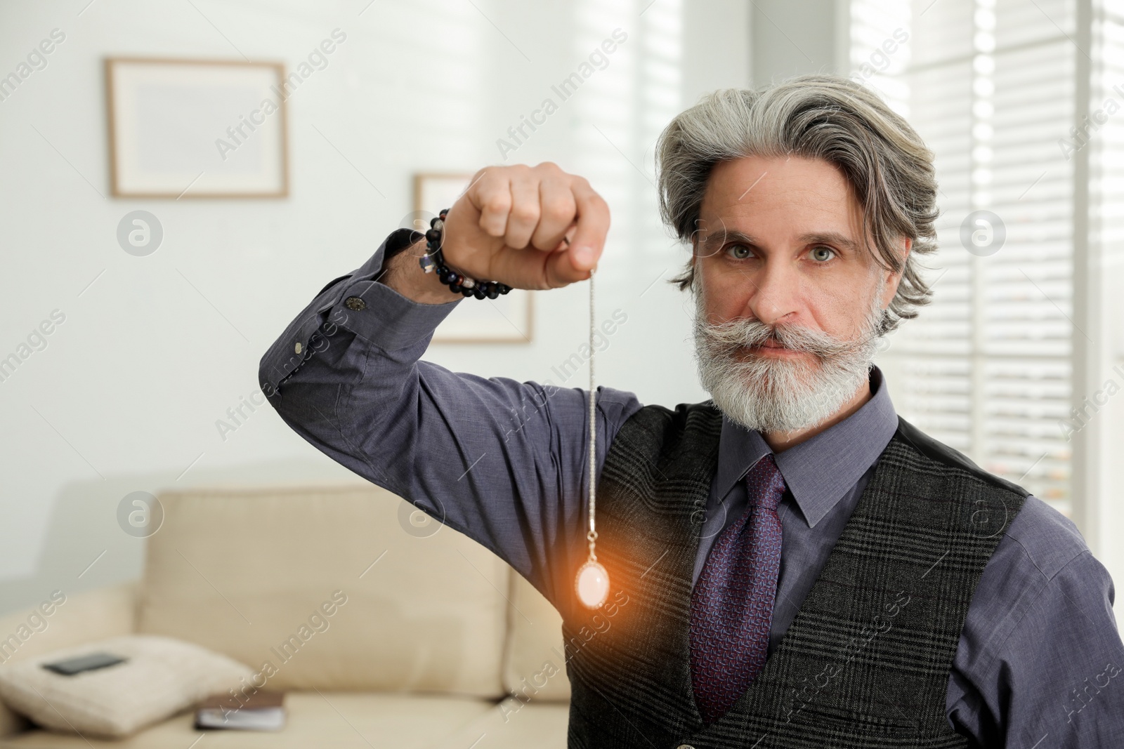 Photo of Psychotherapist with pendulum in office. Hypnotherapy session