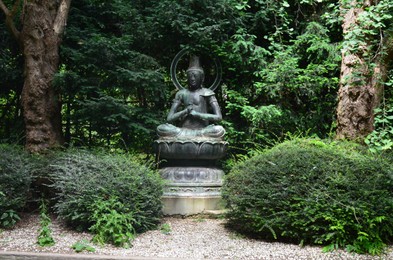 Bronze statue in park among green vegetation