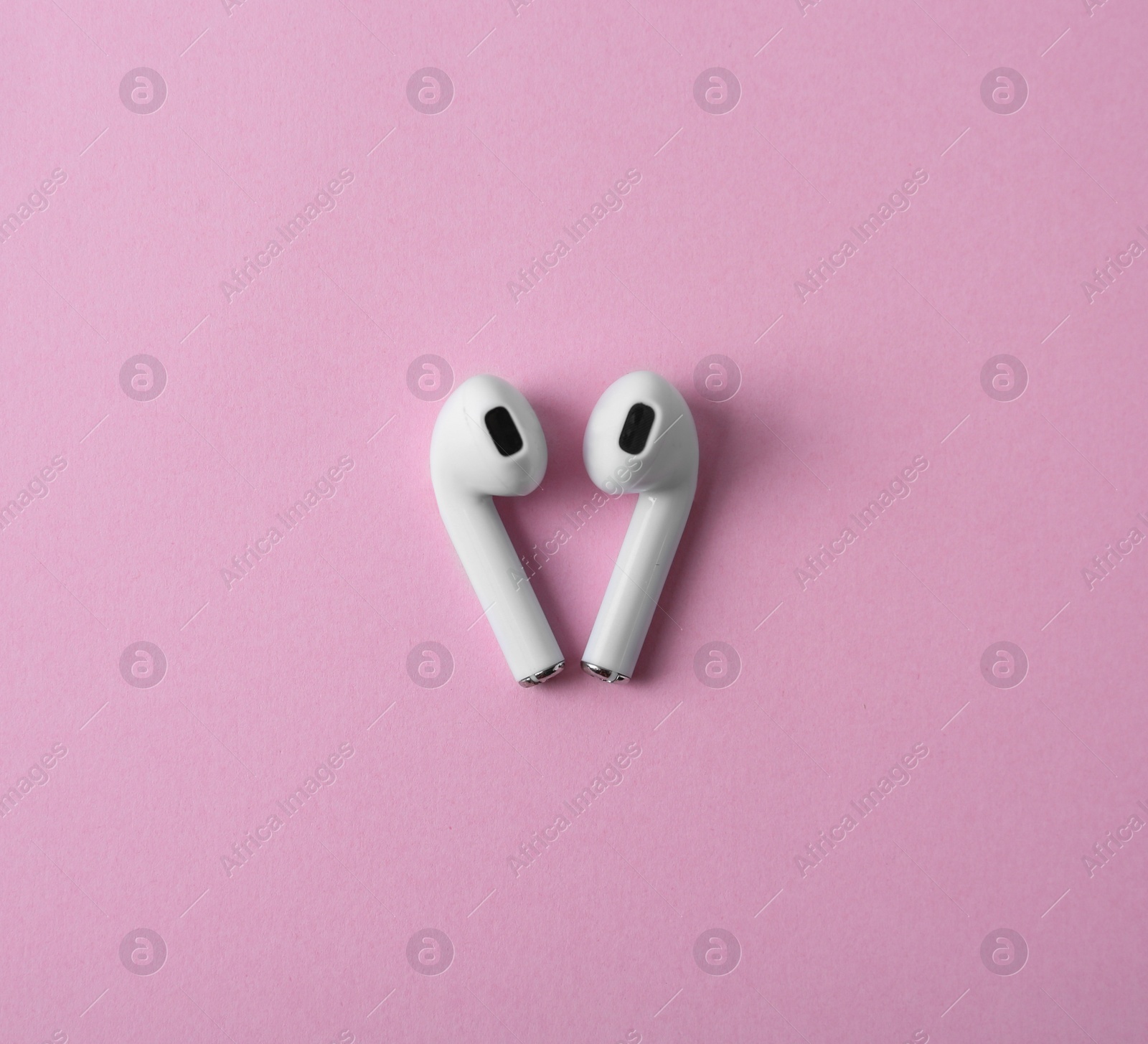 Photo of Modern wireless earphones on pink background, flat lay