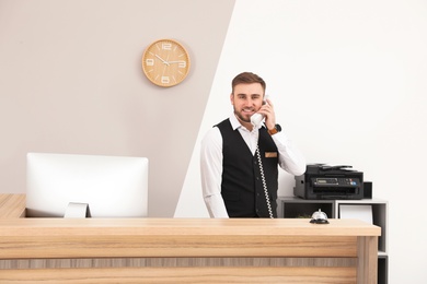 Receptionist talking on telephone at desk in modern hotel