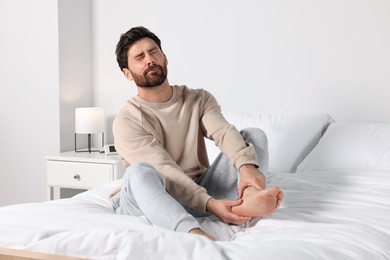 Man suffering from leg pain on bed at home