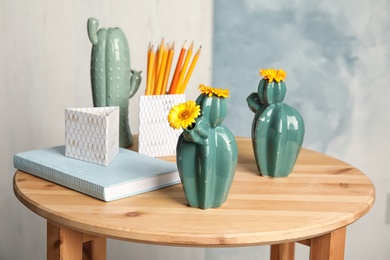 Photo of Trendy cactus shaped vases and stationery on table indoors. Creative decor