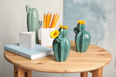 Trendy cactus shaped vases and stationery on table indoors. Creative decor