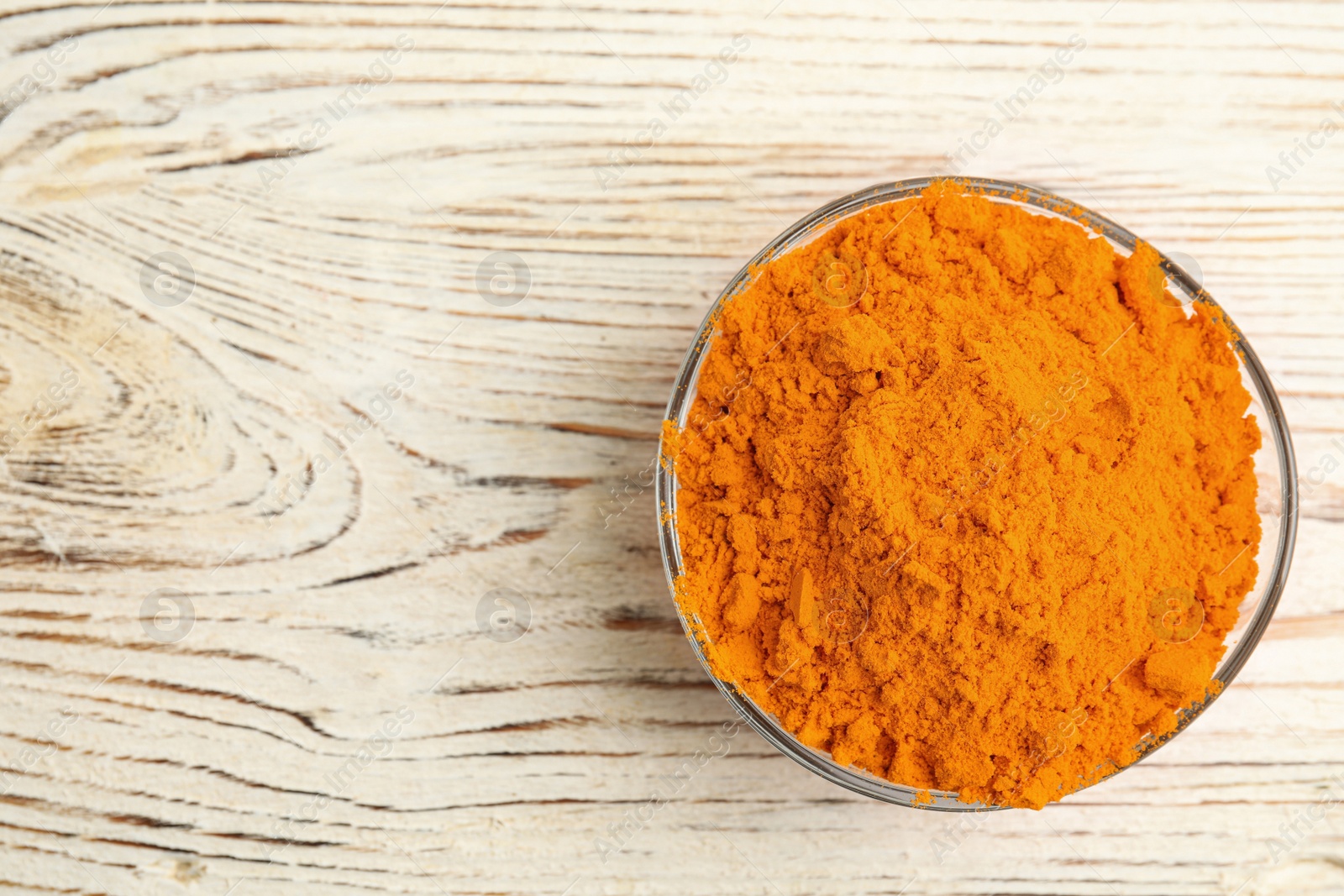 Photo of Bowl with saffron powder on white wooden table, top view. Space for text