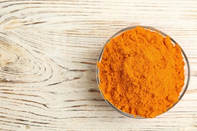 Bowl with saffron powder on white wooden table, top view. Space for text