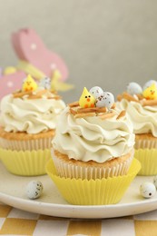 Photo of Tasty Easter cupcakes with vanilla cream on table, closeup