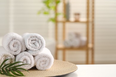 Photo of Spa composition. Towels and palm leaves on white table in bathroom, space for text