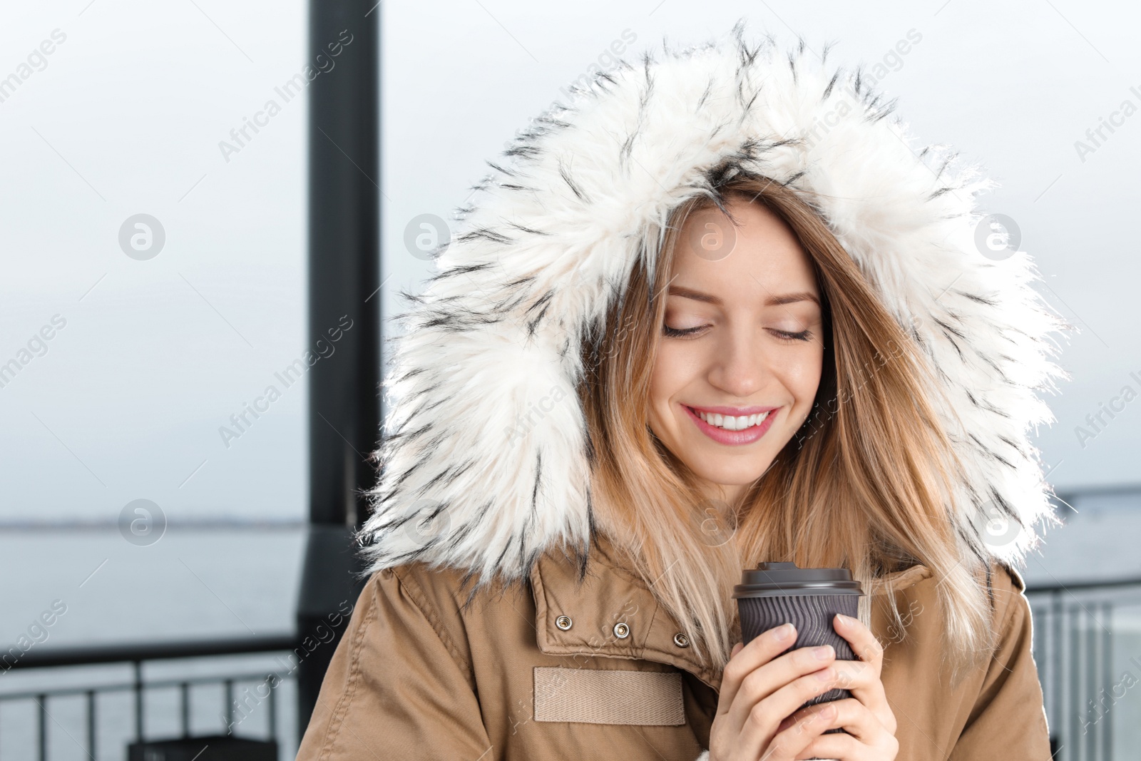 Photo of Young woman with cup of coffee walking outdoors. Space for text