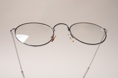 Stylish pair of glasses with metal frame on beige background, closeup