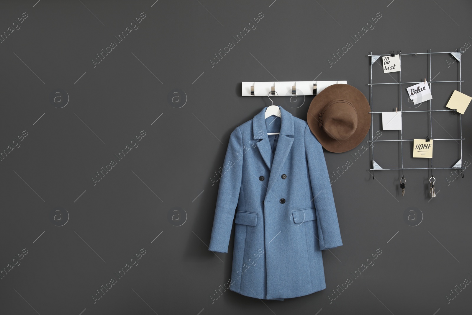 Photo of Coat and hat on wall hanger in stylish hallway interior. Space for text