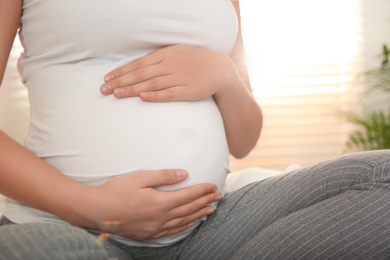 Photo of Young pregnant woman on bed at home, closeup