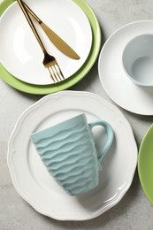 Photo of Beautiful ceramic dishware, cup and cutlery on light grey table, flat lay