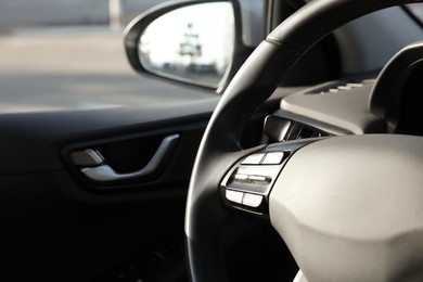 Photo of Black steering wheel inside of modern car, closeup. Space for text