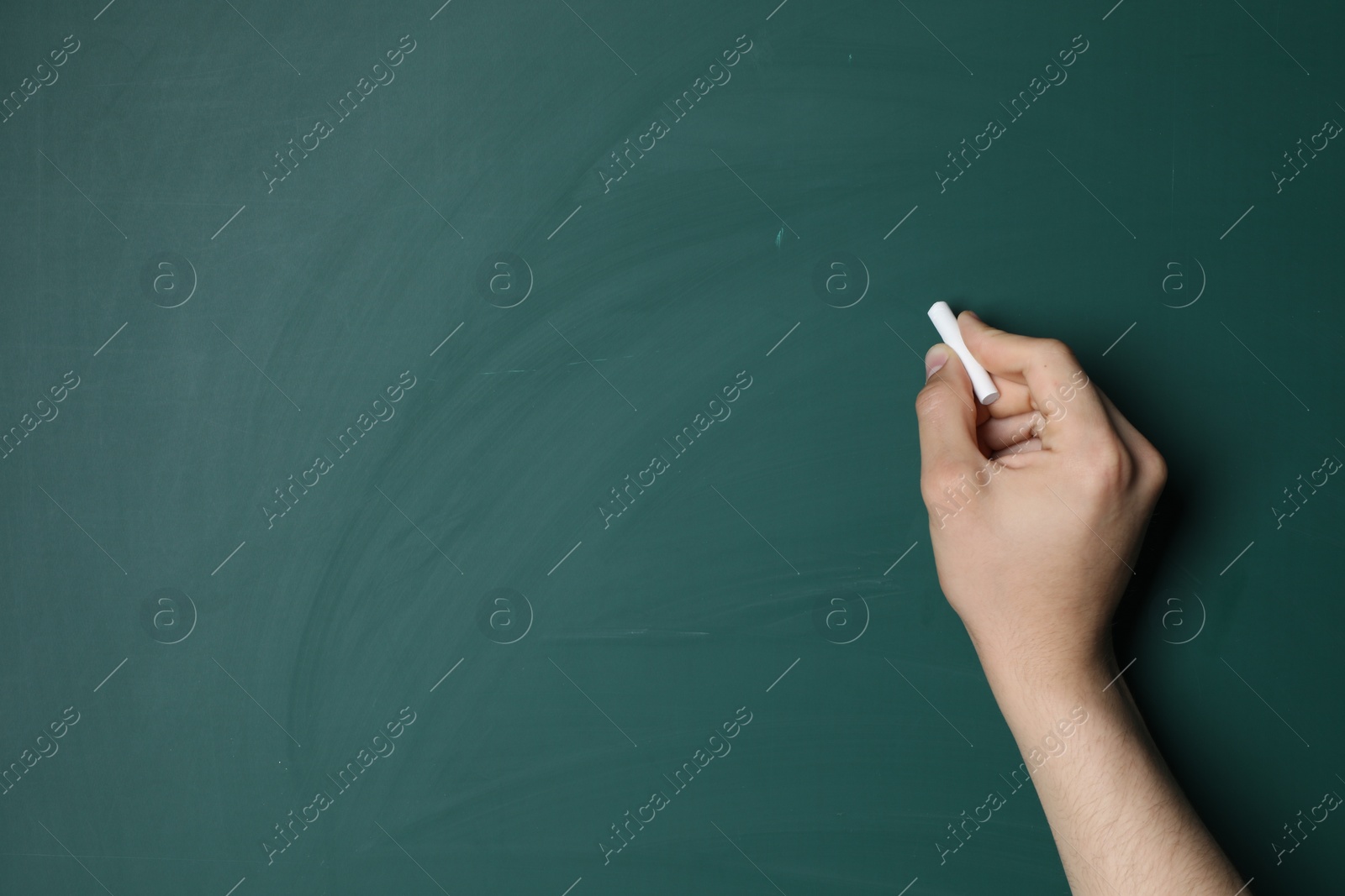 Photo of Teacher writing with chalk on green chalkboard, closeup. Space for text