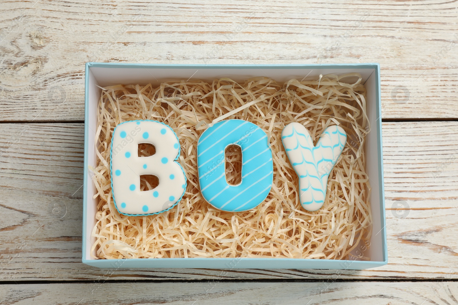 Photo of Baby shower party. Word Boy made of cookies in box on wooden background, top view