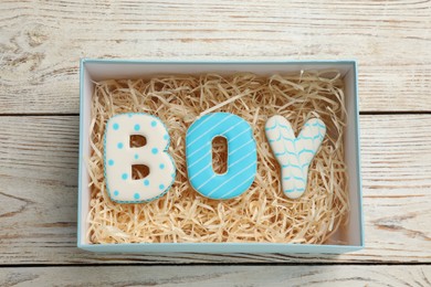 Baby shower party. Word Boy made of cookies in box on wooden background, top view