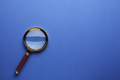 Photo of Magnifying glass on blue background, top view. Space for text