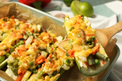 Photo of Baked stuffed zucchini on wooden spatula, closeup