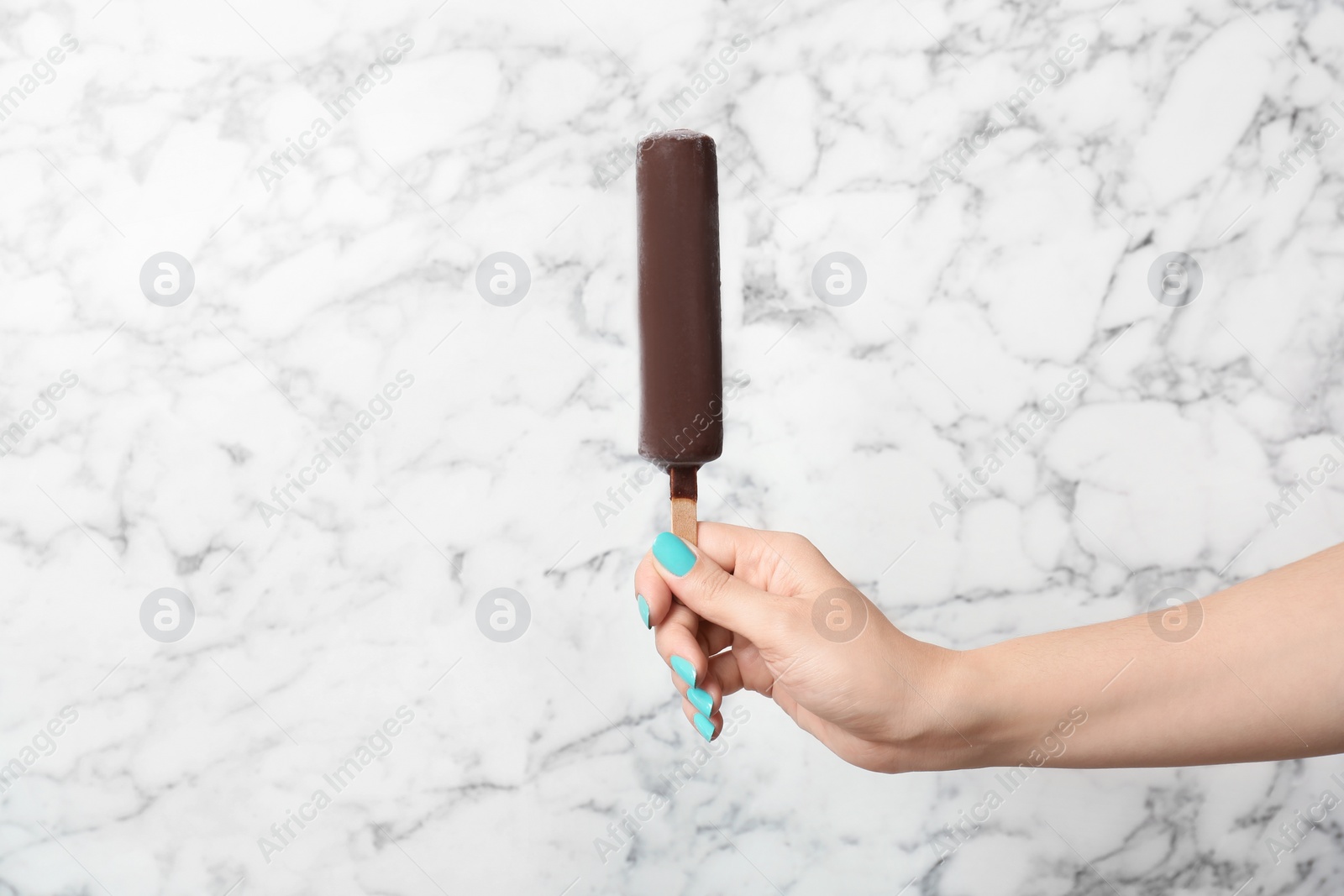 Photo of Woman holding yummy ice cream on marble background. Focus on hand