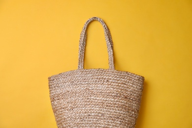 Stylish straw bag on yellow background, top view. Summer accessory