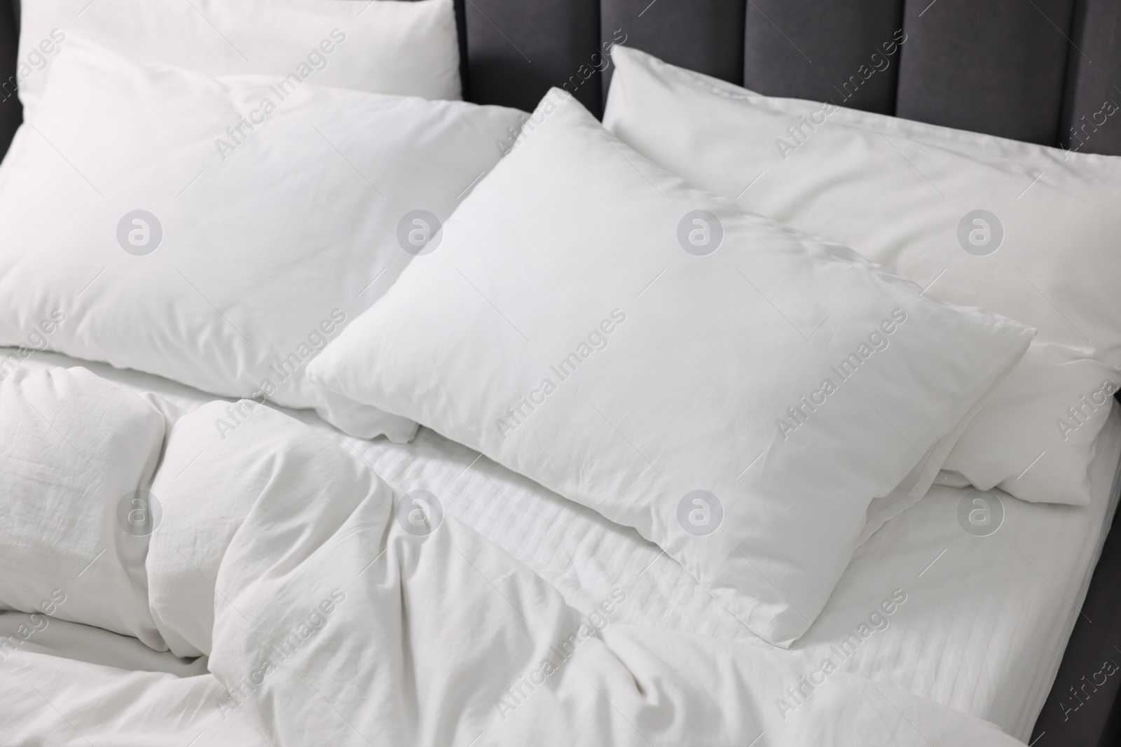 Photo of Soft white pillows and duvet on bed