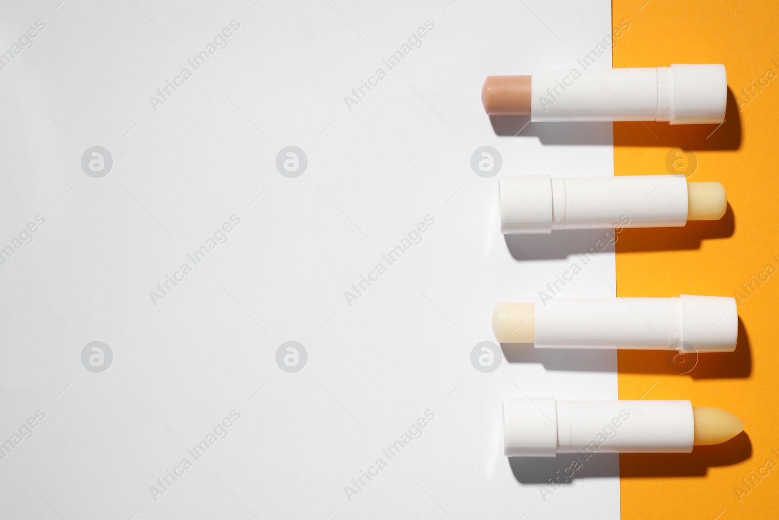 Photo of Hygienic lipsticks on color background, flat lay. Space for text