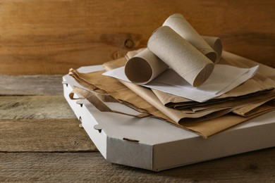 Photo of Stack of different waste paper on wooden table, closeup. Space for text