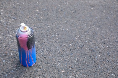 Photo of Used can of spray paint on asphalt road, space for text. Graffiti supplies