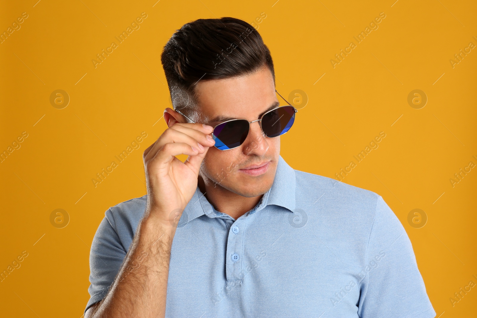 Photo of Handsome man wearing sunglasses on yellow background