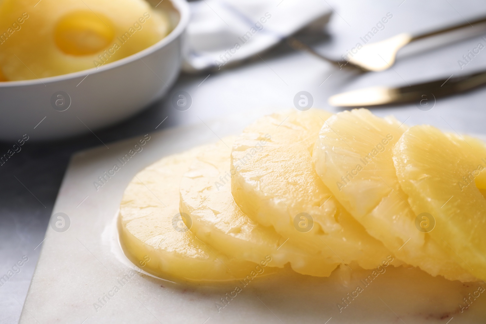 Photo of Delicious canned pineapple rings on marble board, closeup