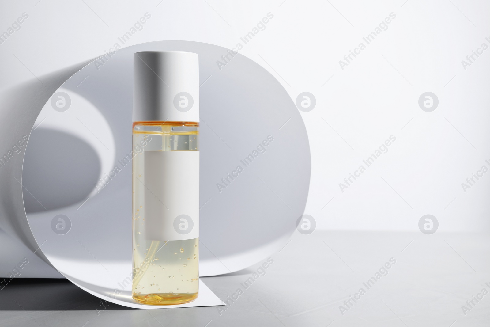 Photo of Bottle of cosmetic product on light grey table. Space for text