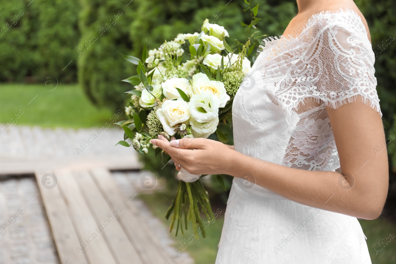 Photo of Bride in beautiful wedding dress with bouquet outdoors, closeup