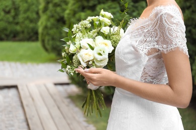 Photo of Bride in beautiful wedding dress with bouquet outdoors, closeup