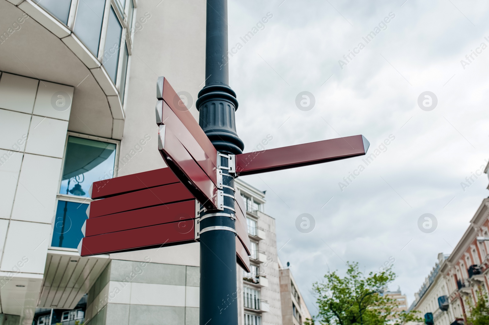 Photo of Post with blank direction signs on city street, low angle view