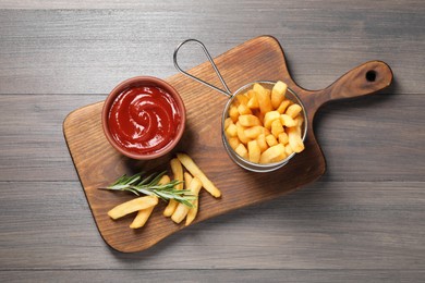 Photo of Delicious French fries served with ketchup on wooden table, top view
