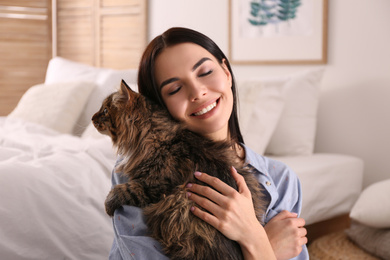 Beautiful young woman with her cute cat in bedroom. Fluffy pet