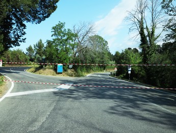 Construction tape over asphalt road on sunny day