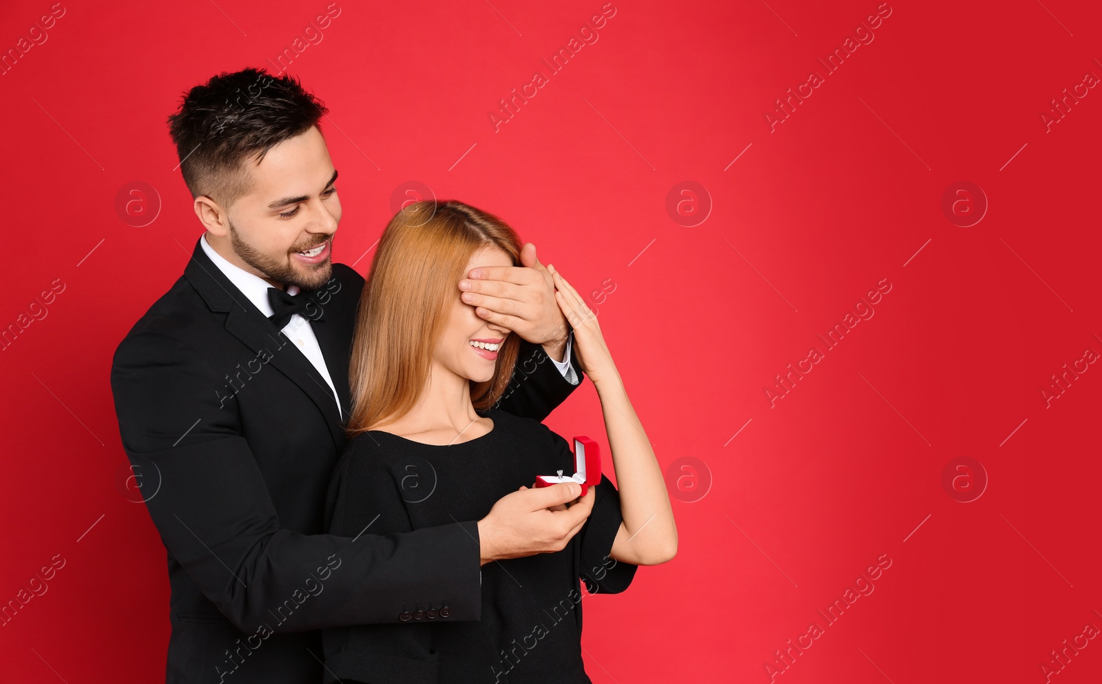Photo of Man with engagement ring making marriage proposal to girlfriend on red background. Space for text
