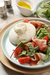 Photo of Delicious burrata salad with tomatoes and prosciutto served on table