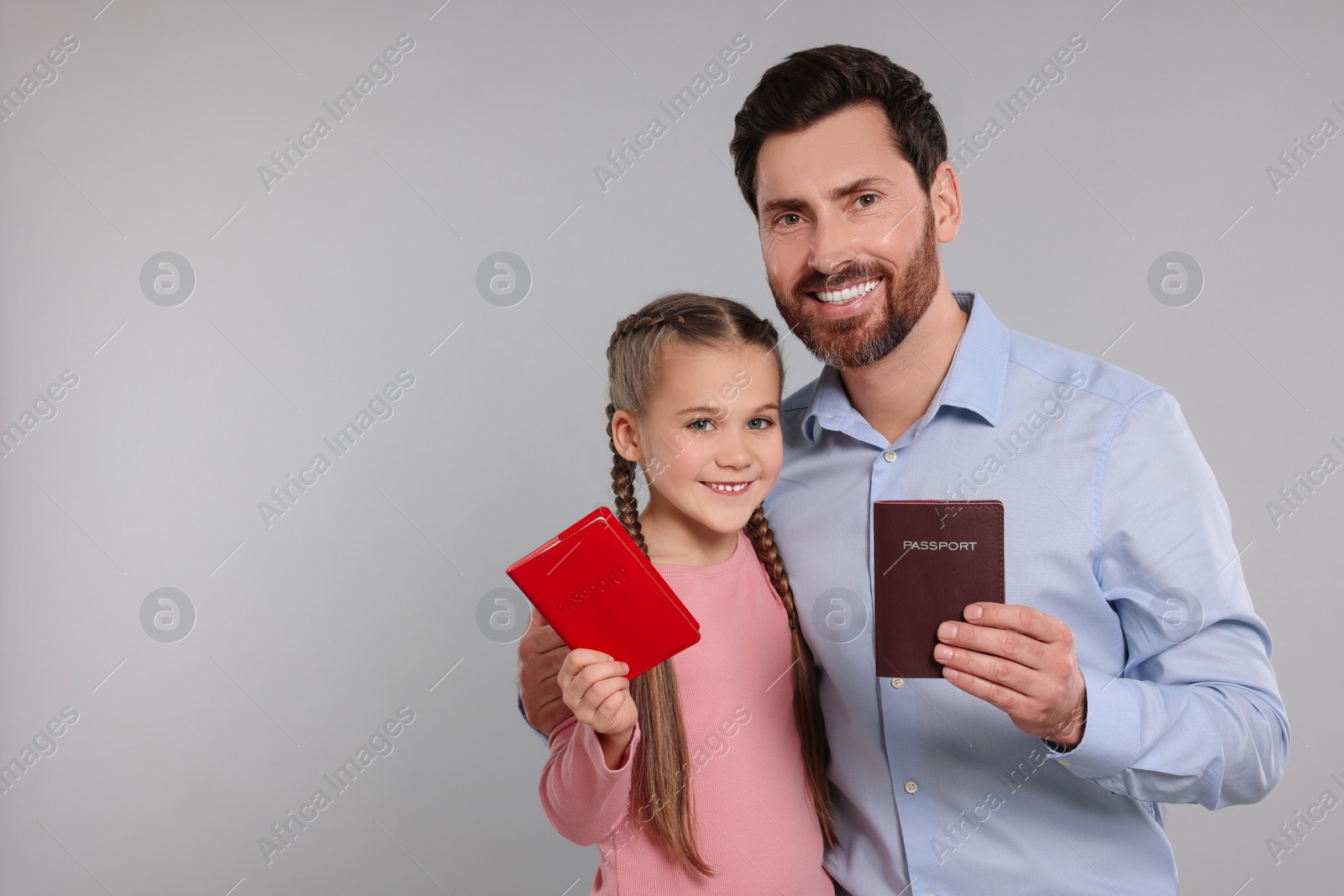 Photo of Immigration. Happy man and his daughter with passports on gray background, space for text