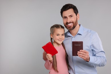 Photo of Immigration. Happy man and his daughter with passports on gray background, space for text