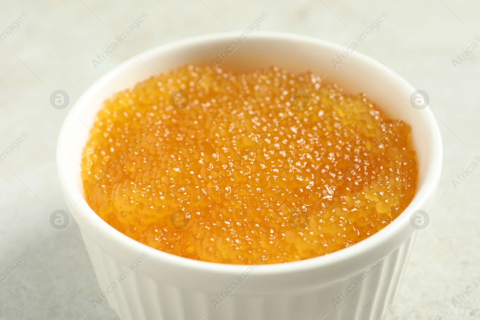 Photo of Fresh pike caviar in bowl on light grey table, closeup