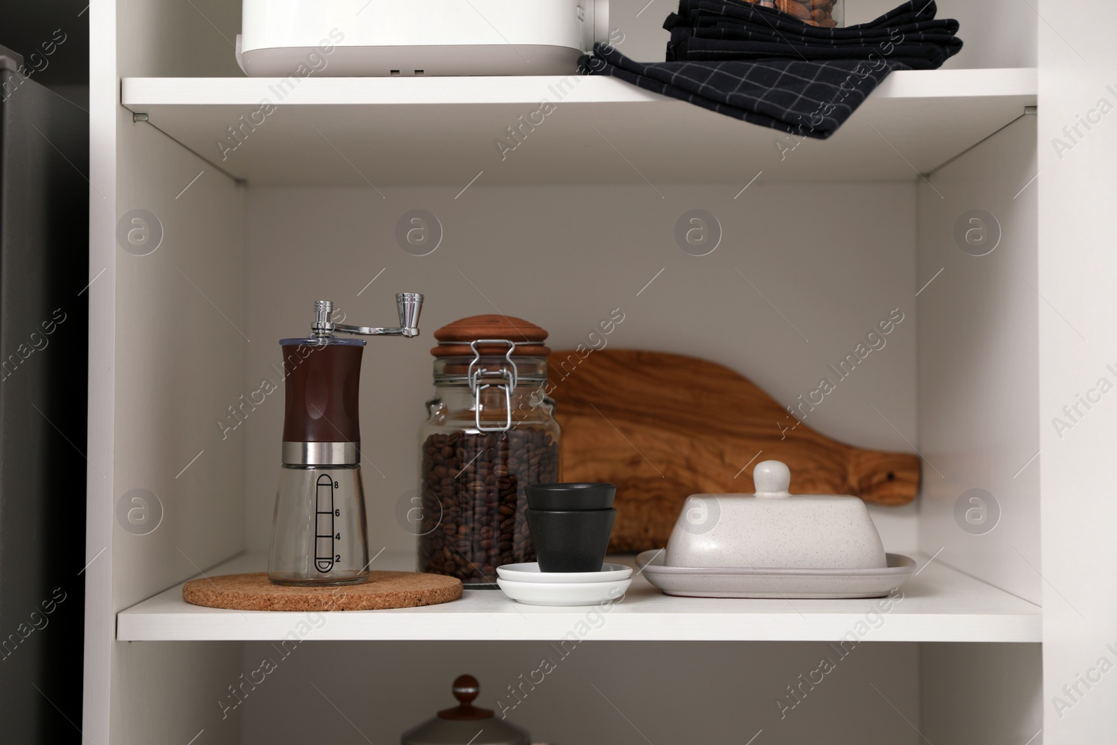 Photo of Manual coffee grinder and other appliances on shelving unit in kitchen