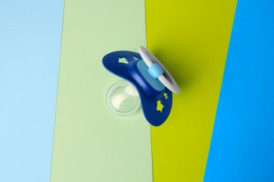 Photo of Baby pacifier on color background, top view