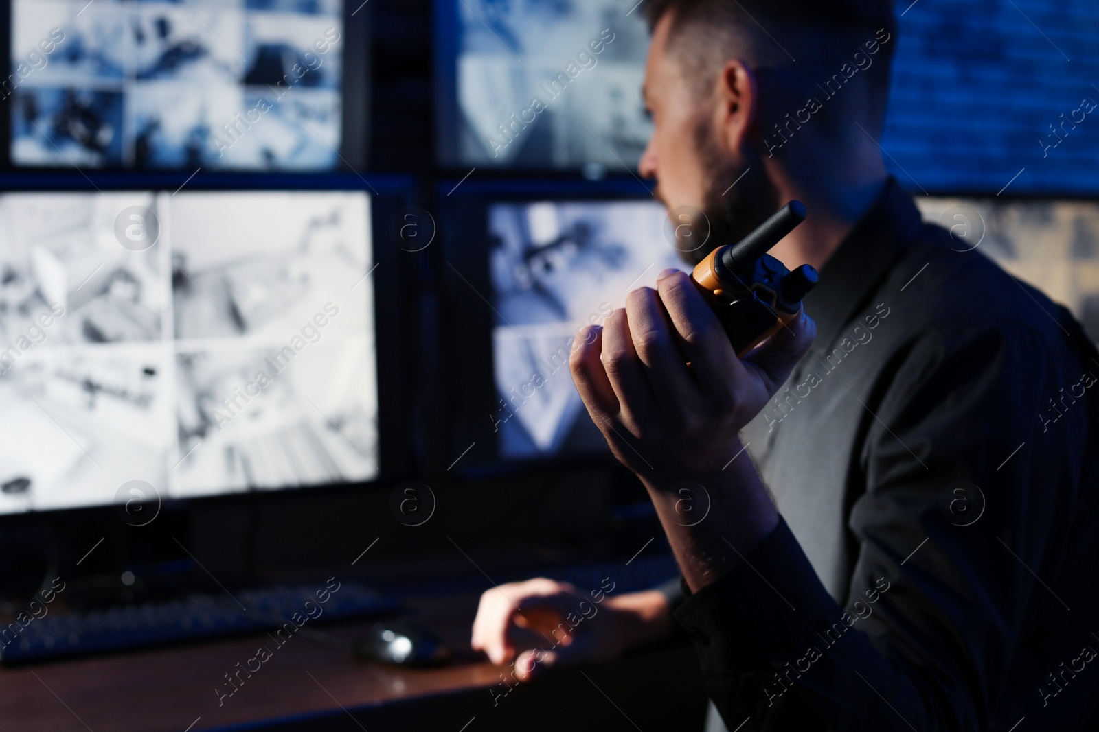 Photo of Male security guard with portable transmitter monitoring modern CCTV cameras indoors