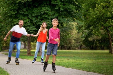 Photo of Little happy boy and his parents roller skating in park